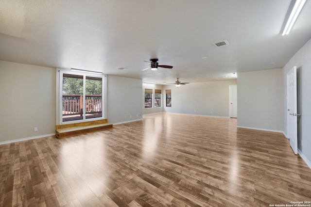 unfurnished living room featuring wood finished floors, a ceiling fan, and baseboards