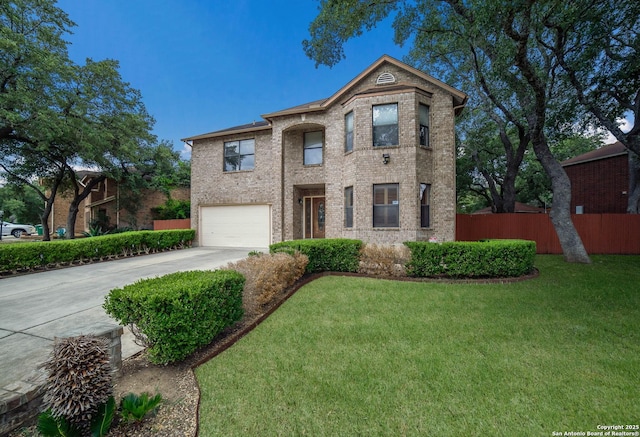 traditional-style home featuring concrete driveway, an attached garage, fence, brick siding, and a front lawn