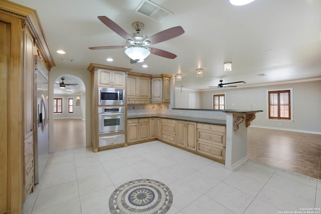 kitchen featuring light brown cabinetry, kitchen peninsula, a healthy amount of sunlight, and stainless steel appliances