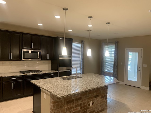 kitchen featuring appliances with stainless steel finishes, sink, an island with sink, and hanging light fixtures