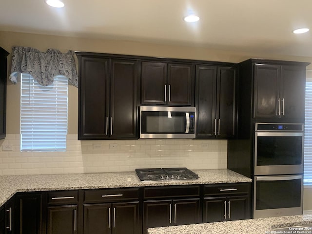 kitchen featuring tasteful backsplash, appliances with stainless steel finishes, light stone countertops, and sink