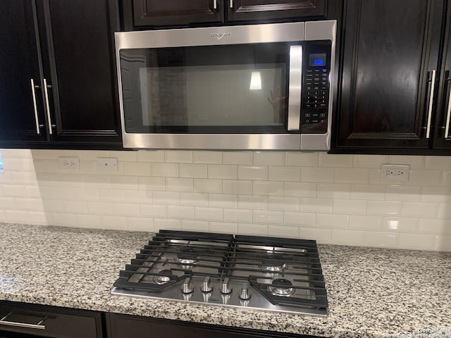 interior details featuring stainless steel appliances, light stone counters, and decorative backsplash