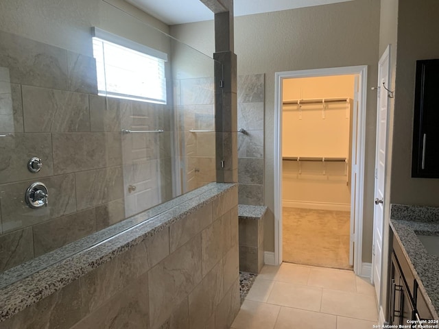 bathroom featuring tile patterned flooring, vanity, and a tile shower