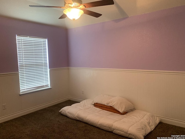 living area featuring ceiling fan and dark colored carpet