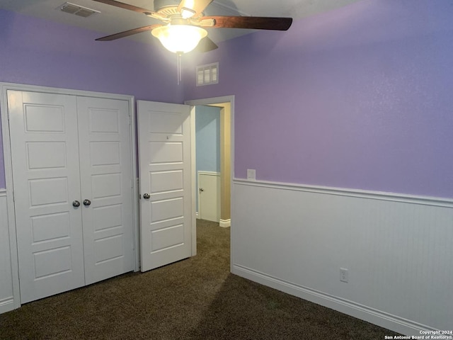 unfurnished bedroom with a closet, ceiling fan, and dark colored carpet