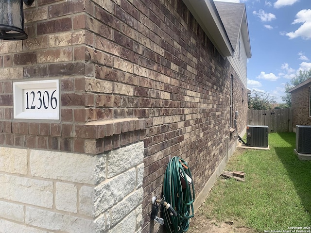 view of side of property with central AC unit and a lawn