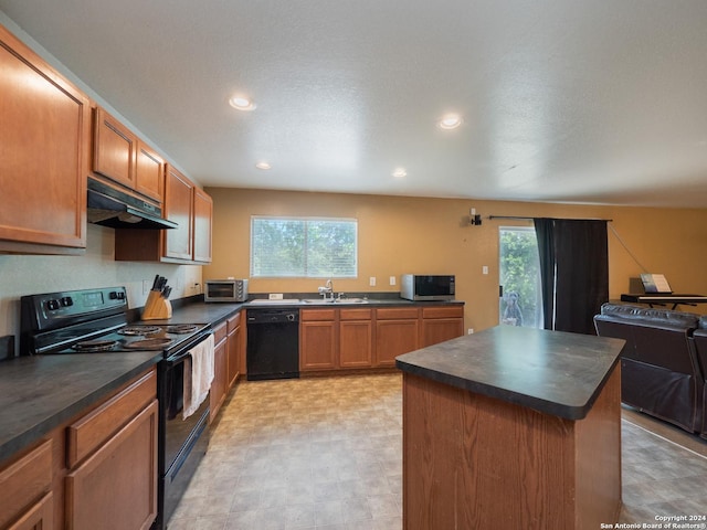 kitchen with plenty of natural light, black appliances, sink, and a kitchen island