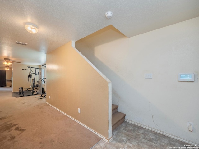 stairway featuring a textured ceiling, ceiling fan, and carpet floors