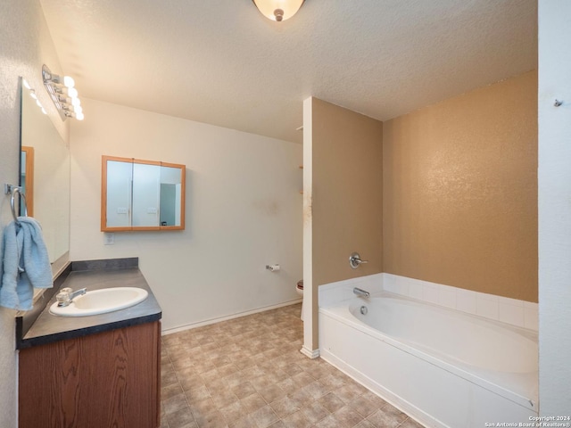 bathroom with a textured ceiling, a bathtub, vanity, and toilet