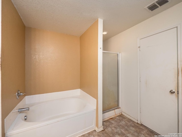 bathroom featuring a textured ceiling and shower with separate bathtub