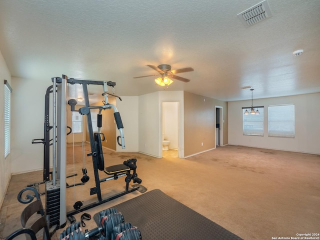 workout area with ceiling fan with notable chandelier, a textured ceiling, and light carpet