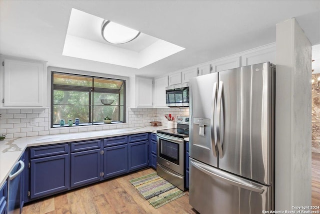 kitchen featuring tasteful backsplash, white cabinetry, light hardwood / wood-style flooring, appliances with stainless steel finishes, and blue cabinets