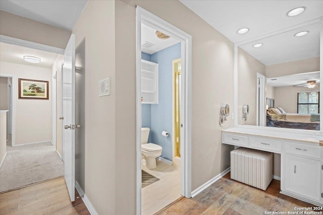 bathroom with toilet, vanity, ceiling fan, wood-type flooring, and radiator