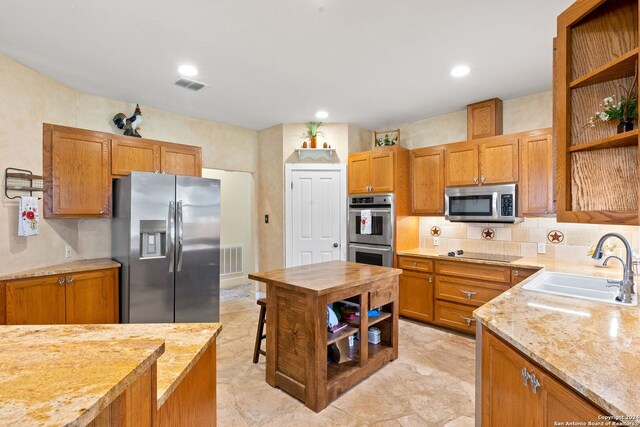 kitchen featuring light tile patterned floors, light stone counters, stainless steel appliances, decorative backsplash, and sink