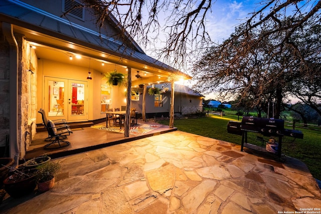 patio terrace at dusk with a yard, area for grilling, and french doors