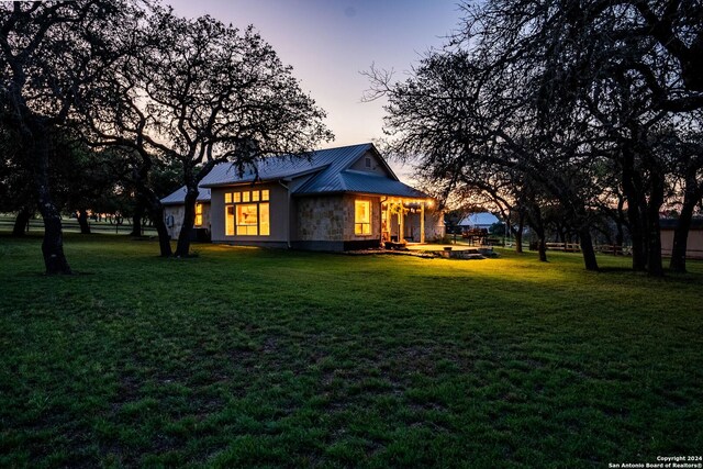 back house at dusk featuring a yard