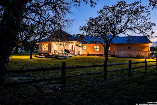 view of front of property featuring metal roof, stone siding, a front lawn, and fence private yard