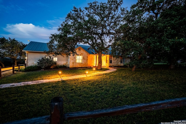 view of front facade featuring stone siding, a front yard, fence, and stucco siding