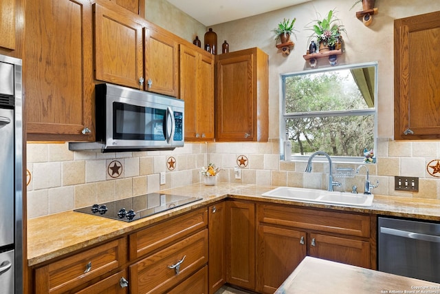 kitchen with brown cabinetry, backsplash, stainless steel appliances, and a sink