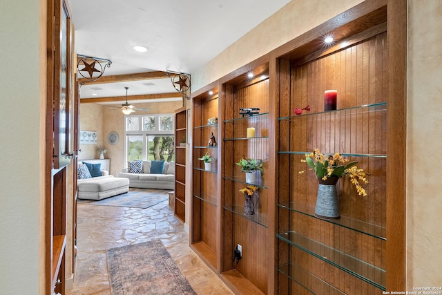 hall with beam ceiling and stone tile floors