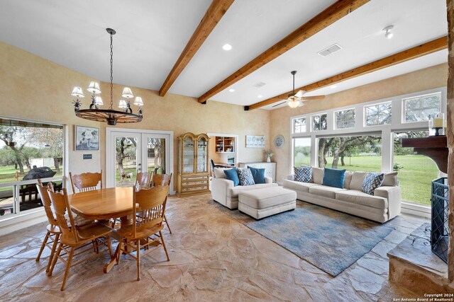 dining space with ceiling fan with notable chandelier, beamed ceiling, and plenty of natural light