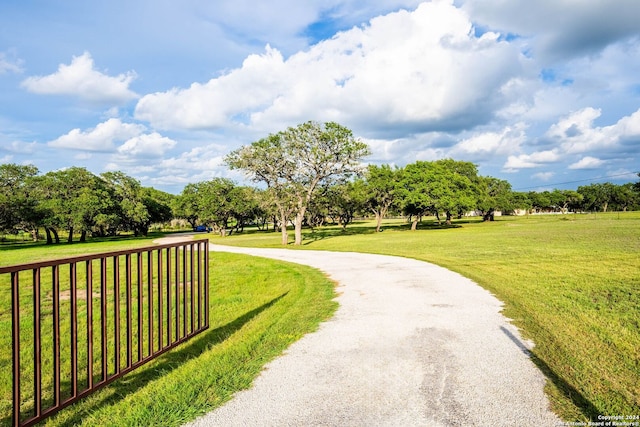 view of home's community featuring a lawn, gravel driveway, and fence