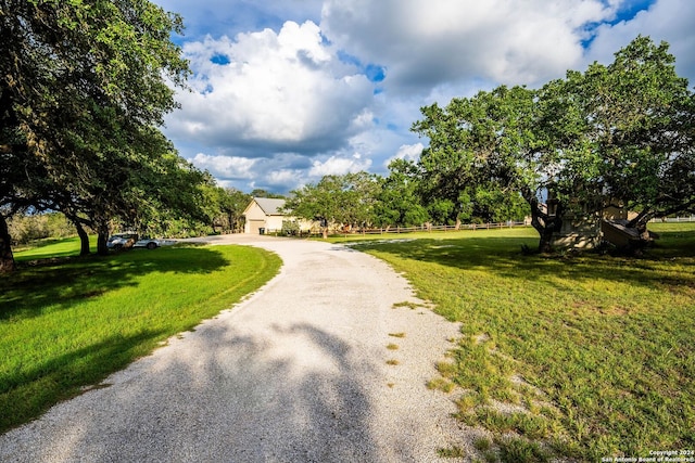 surrounding community with a yard and gravel driveway