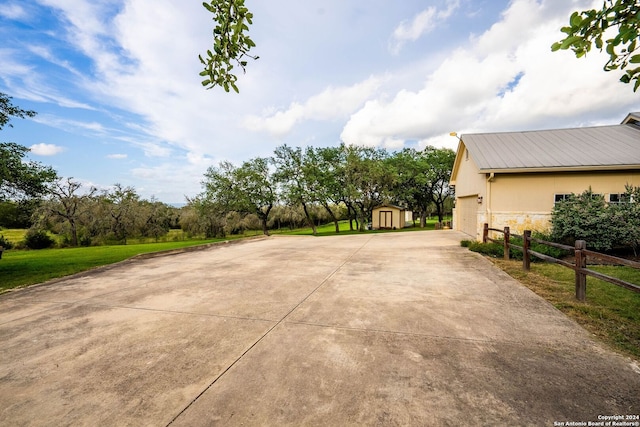 view of patio / terrace featuring a garage, an outdoor structure, fence, and a storage unit