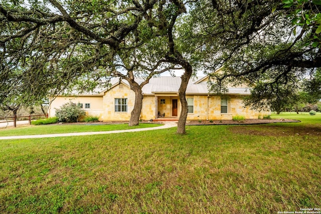 ranch-style home with stone siding, metal roof, and a front lawn