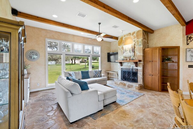 living room with beam ceiling, a stone fireplace, and ceiling fan