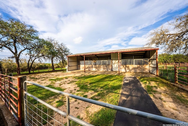 view of front of property with metal roof, a rural view, an outdoor structure, and an exterior structure