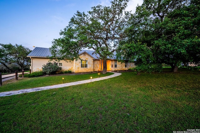 ranch-style house featuring stone siding, a front lawn, metal roof, and a standing seam roof