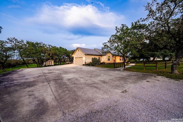 view of front facade featuring a garage, fence, concrete driveway, a storage unit, and a front yard