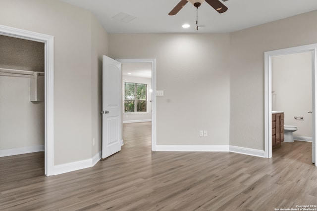 unfurnished bedroom with a closet, connected bathroom, hardwood / wood-style floors, and ceiling fan