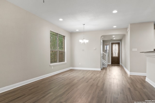 unfurnished dining area featuring an inviting chandelier and hardwood / wood-style flooring