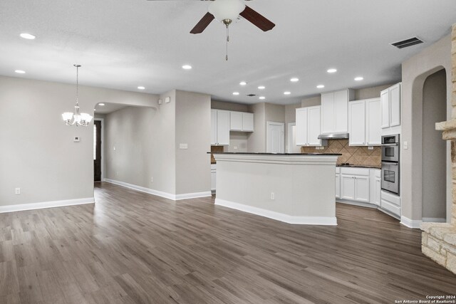 kitchen with white cabinetry, dark hardwood / wood-style flooring, ceiling fan with notable chandelier, decorative backsplash, and double oven