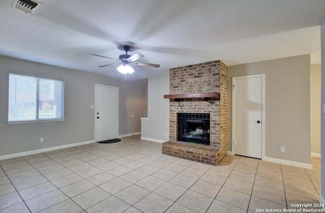 unfurnished living room with a brick fireplace, ceiling fan, and light tile patterned floors