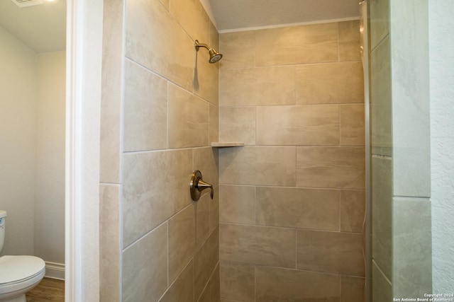 bathroom featuring a tile shower and toilet