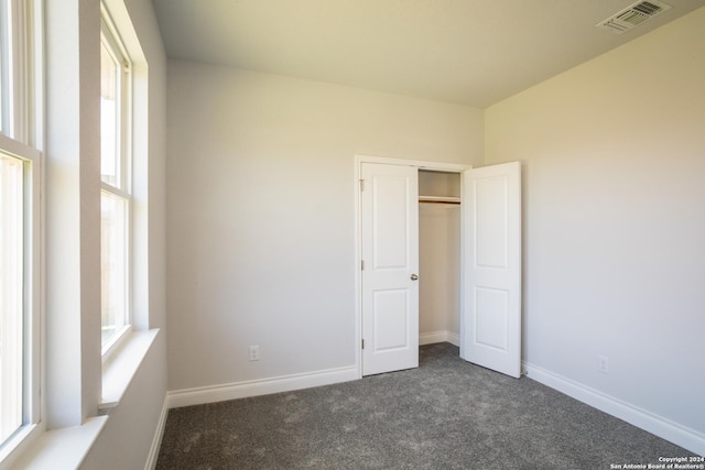 unfurnished bedroom featuring a closet and dark colored carpet