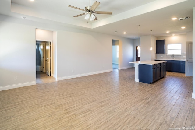 kitchen with sink, a center island, decorative light fixtures, and a tray ceiling