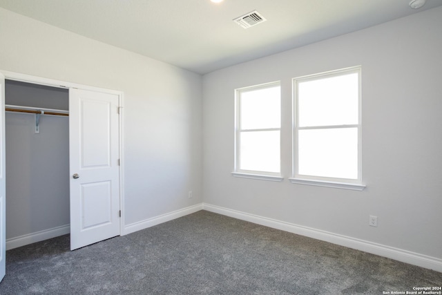 unfurnished bedroom with a closet and dark carpet