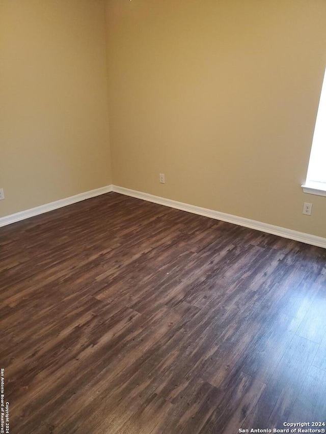 unfurnished room with dark wood-type flooring