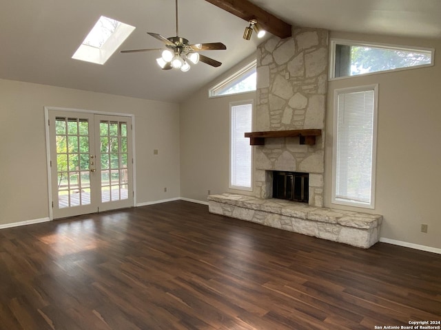 unfurnished living room featuring a fireplace, french doors, ceiling fan, vaulted ceiling with skylight, and dark hardwood / wood-style floors