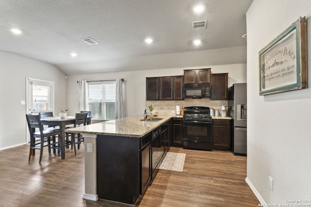 kitchen featuring wood-type flooring, backsplash, kitchen peninsula, and black appliances