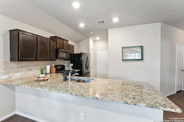 kitchen featuring kitchen peninsula, decorative backsplash, light stone countertops, dark brown cabinetry, and black appliances