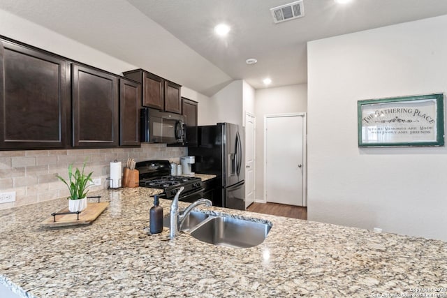 kitchen with backsplash, stainless steel refrigerator with ice dispenser, sink, black range with gas cooktop, and light stone countertops