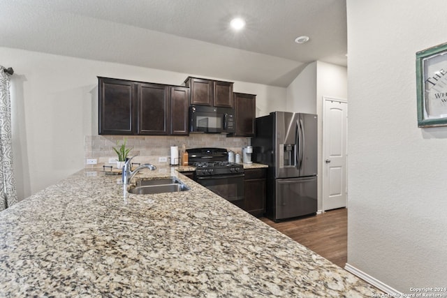 kitchen featuring black appliances, decorative backsplash, sink, light stone countertops, and dark brown cabinets