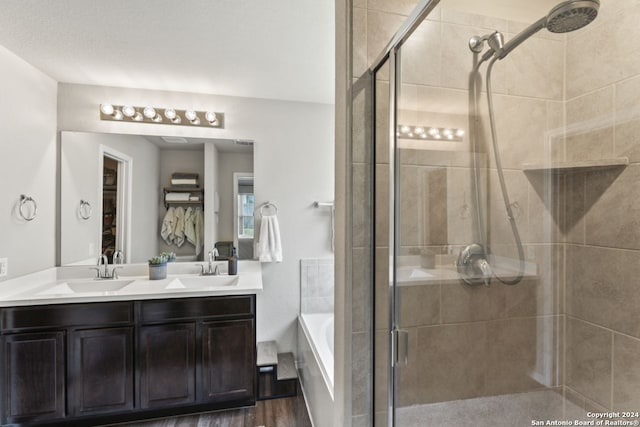 bathroom with wood-type flooring, vanity, and plus walk in shower