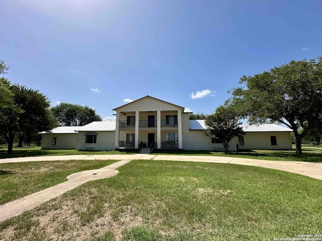 neoclassical home with a balcony and a front yard