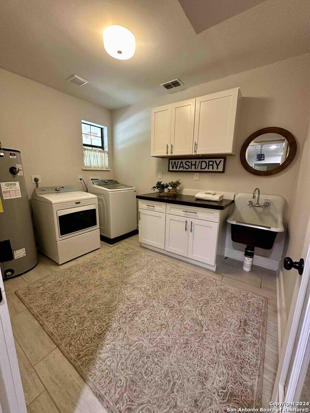 kitchen featuring white cabinetry, washing machine and dryer, water heater, and light tile patterned floors